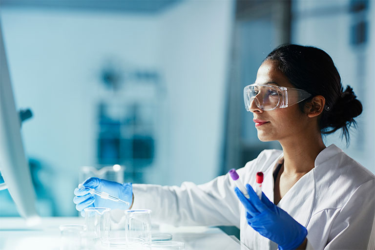 A woman in a lab coat is focused on conducting an experiment at a laboratory workstation.