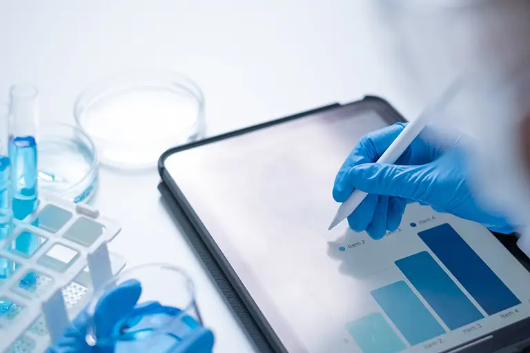 A person wearing blue gloves is interacting with a tablet computer, focused on the screen.